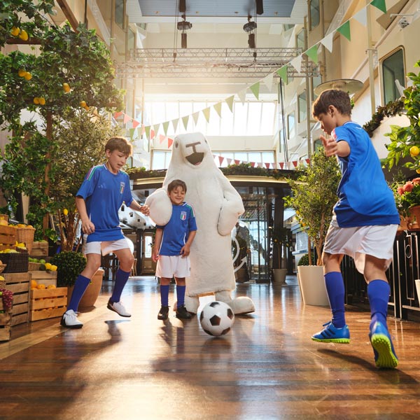 Harry the Seal plays football with boys in football shirts on the Promenade